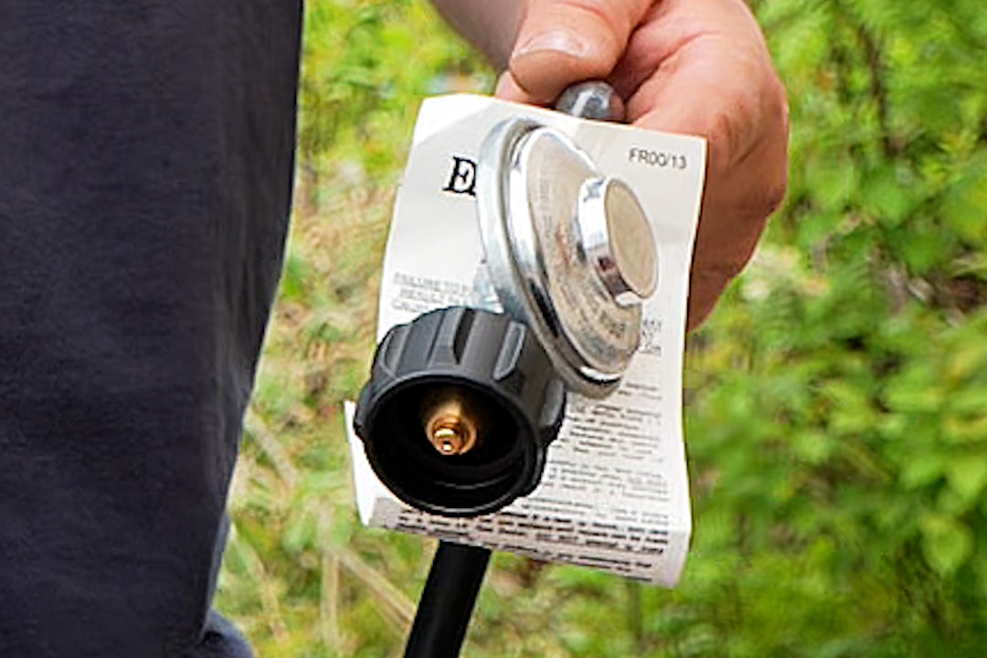 Hand holding the HOTTAP V2 gas hose regulator fitting, still with its paper tag attached