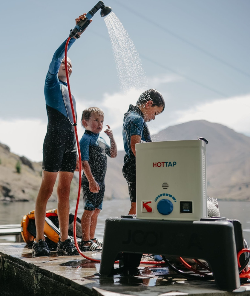 Kids in wetsuits showering on a dock