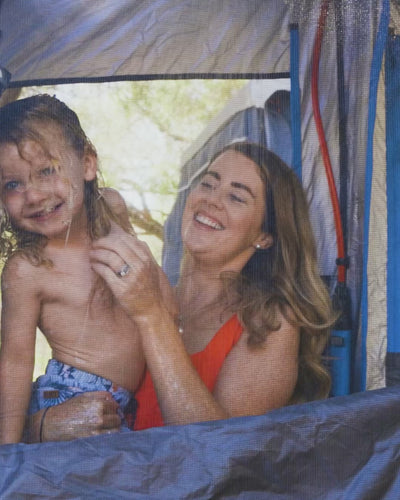 Mother and child showering together inside an ensuite tent using the HOTTAP V2.