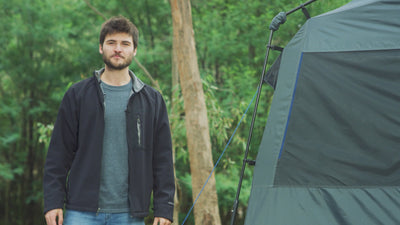 Man giving a thumbs up outside the Joolca Ensuite Single shower tent in a forest campsite.
